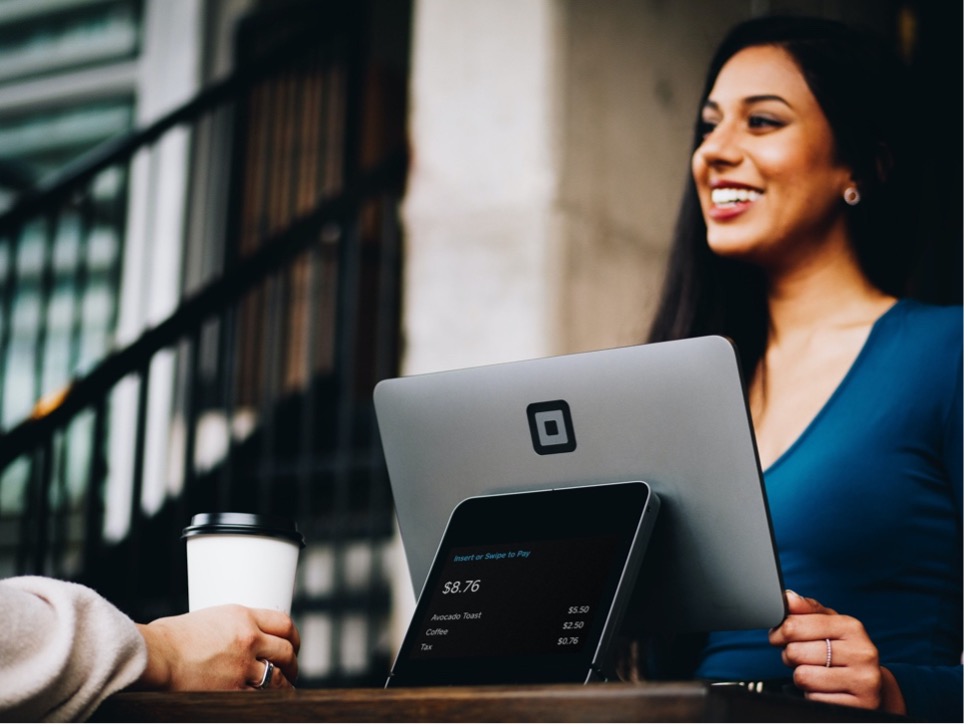 A woman smiles brightly while working on her laptop, showcasing a moment of joy and productivity.