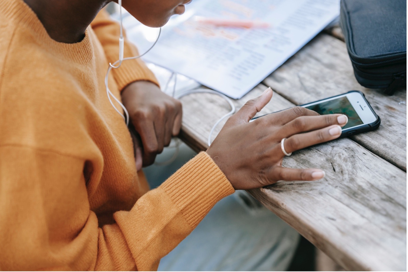 African Girl sitting on a bench on a public place for study while listening songs